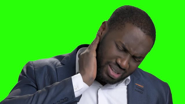Afro american man suffering from neck ache. Stressed dark-skinned businessman has terrible pain in his neck on chroma key background close up. Causes of neck pain.