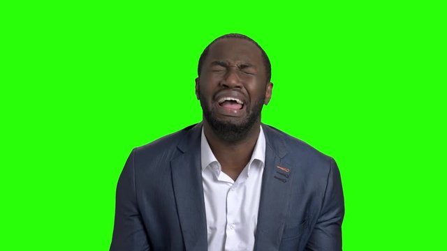 Desperate businessman crying on green screen. Afro american man in business suit in full despair on Alpha Channel background.