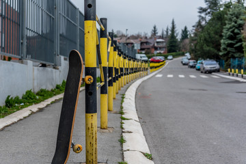 Skateboard left on street black yellow fence, extreme sports concept
