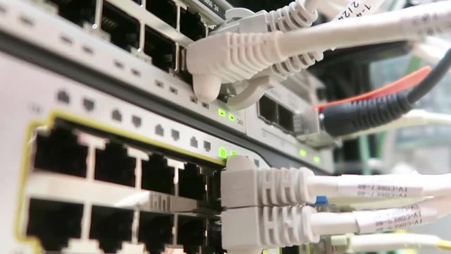 One male IT engineer working in a data center with rows of server racks and super computers. He is checking all of the cables and other equipment. Сhecking the network cable RG45.