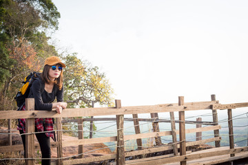 Tourist young woman wearing hat enjoying stand in wood bridge on the mountains.