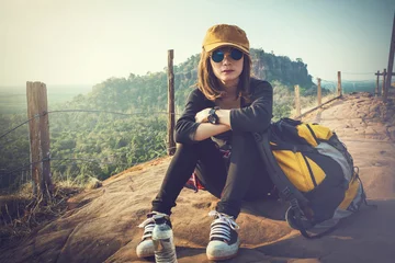 Tuinposter Tourist young woman wearing hat enjoying sitting on the mountain. © Chayanin Wongpracha