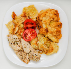 Fried chicken with cabbage in batter and tomatoes on a white plate and on a white background