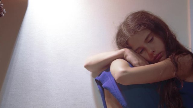sad girl upset embraces her feet. is depressed and suicidal little lamentable girl schoolgirl sadness misses the night in bed concept childhood family. the problem of education in the family. sad
