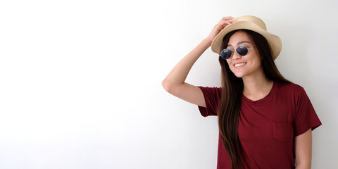 Portrait of young cute asian woman wearing sunglasses and hat smiling over white wall background with copy space for text