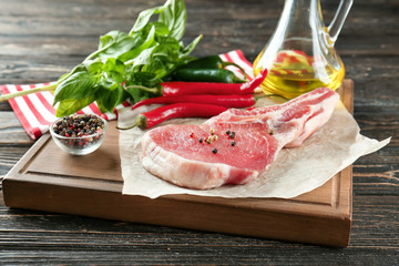 Board with fresh raw rib and vegetables on wooden table