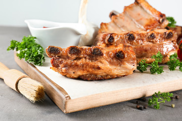 Wooden board with delicious grilled ribs on table © Africa Studio