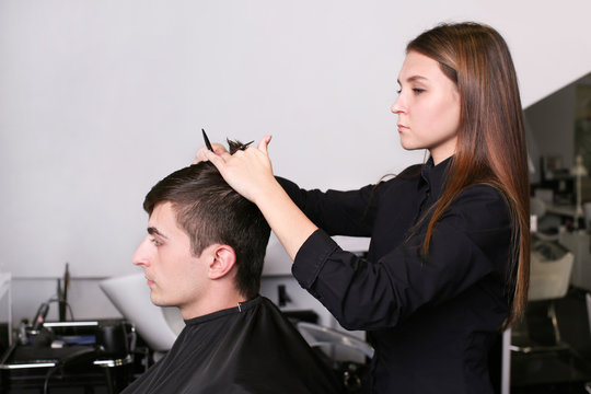 Professional stylist cutting client's hair in salon