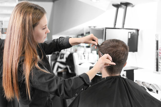Female hairdresser cutting client's hair in salon