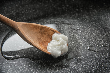 Wooden spoon with coconut oil in frying pan, closeup. Healthy cooking
