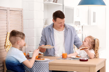 Father and cute little children having breakfast with tasty toasted bread at table