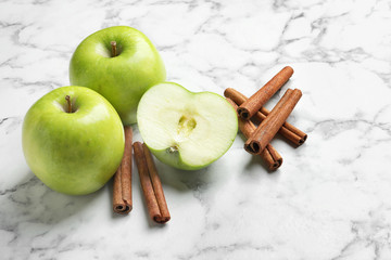 Fresh apples and cinnamon sticks on marble table