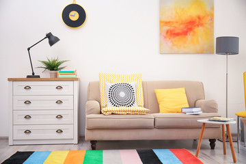 Modern room interior with comfortable sofa and rainbow carpet