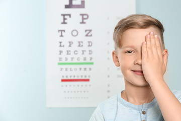 Cute little boy covering eye in ophthalmologist office