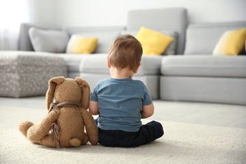 Little boy with toy sitting on floor in living room. Autism concept - obrazy, fototapety, plakaty