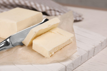 Cutting tasty fresh butter on wooden board, closeup