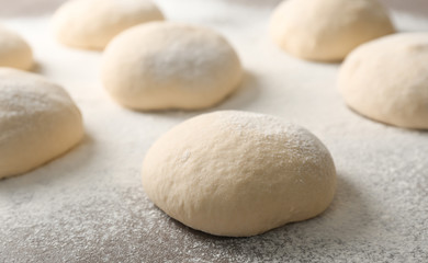 Fresh raw dough with flour on table