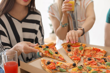 Young people eating delicious pizza at table, closeup