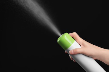 Woman spraying air freshener on black background, closeup