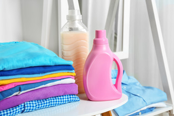 Stack of clean clothes and bottles with detergent on table