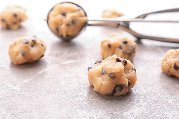 Cookie dough with chocolate chips and scoop on light background