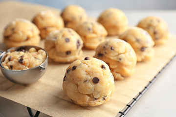 Raw cookie dough with chocolate chips and scoop on parchment paper, closeup