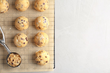 Raw cookie dough with chocolate chips and scoop on parchment paper, top view