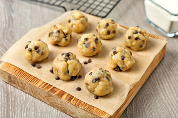 Raw cookie dough with chocolate chips on wooden board