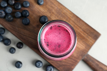 Jar with healthy detox smoothie and blueberries on table, top view