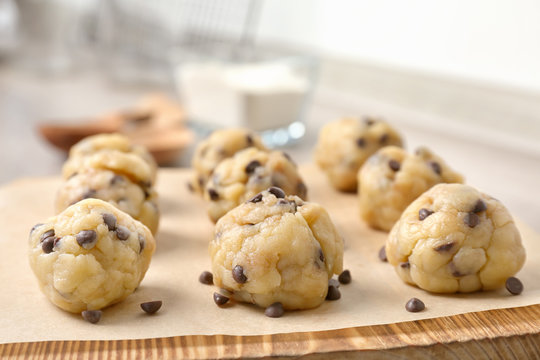 Raw cookie dough with chocolate chips on wooden board