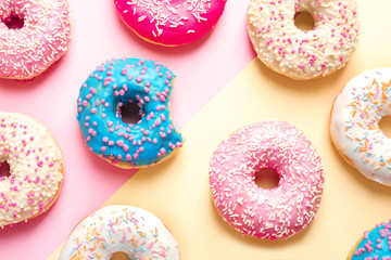 Fototapeta na wymiar Delicious glazed doughnuts on color background, top view