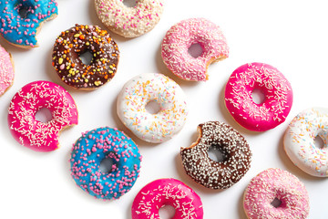 Delicious doughnuts with sprinkles on light background, top view
