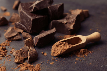 Scoop with cocoa powder and tasty chocolate on dark table
