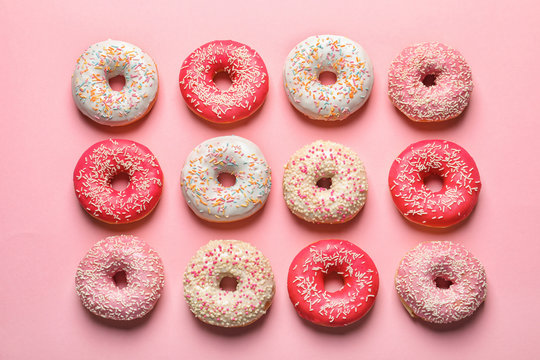 Delicious glazed doughnuts on color background, top view