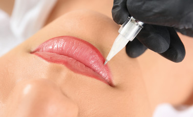 Young woman getting permanent makeup on lips in beautician salon, closeup - obrazy, fototapety, plakaty