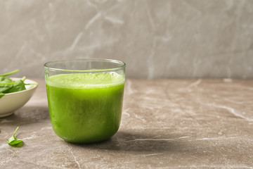 Glass with delicious detox juice and spinach on table