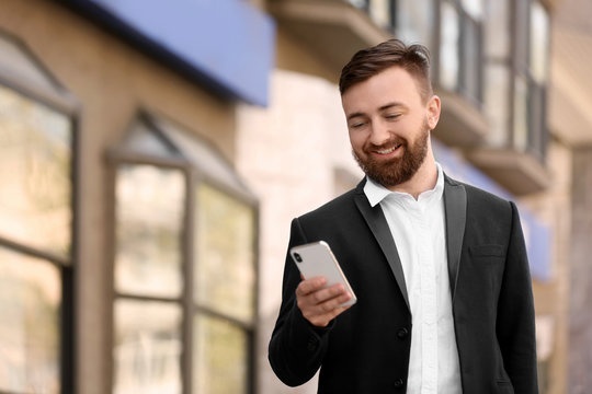 Portrait of young businessman with smartphone outdoors