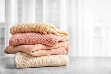 Stack of warm knitted clothes on table