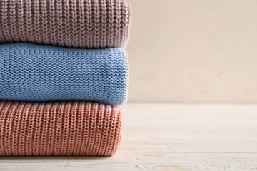 Stack of warm knitted clothes on table