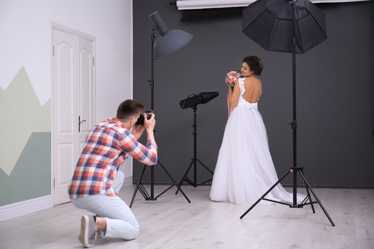 Professional photographer taking photo of beautiful bride in studio