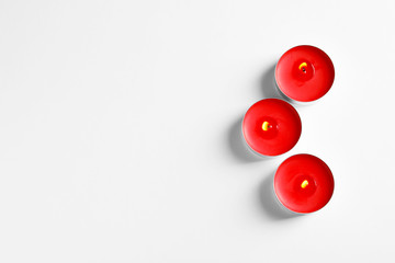 Burning wax candles on white background, top view