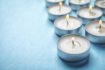 Small wax candles burning on color background, closeup