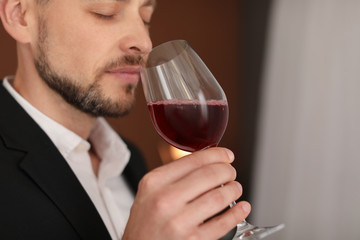 Young man with glass of wine indoors
