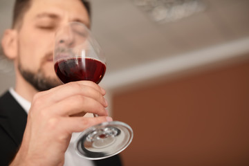 Young man with glass of wine indoors