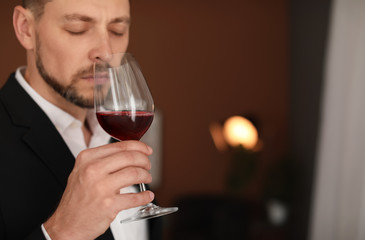 Young man with glass of wine indoors