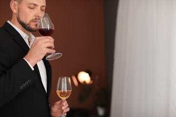 Young man with glasses of wine indoors