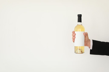 Man holding bottle of wine on light background