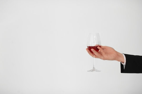 Man holding glass of wine on light background