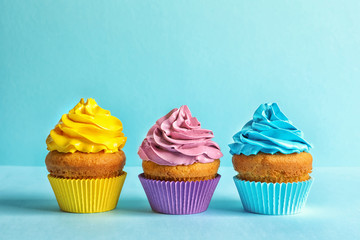 Delicious birthday cupcakes with cream on color background