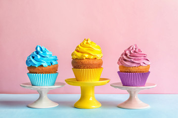 Delicious birthday cupcakes with cream on color background